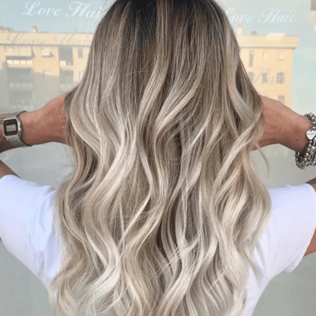 Person with wavy, blonde balayage hair after using Muvo Balayage Shampoo For Blondes 500ml showcasing her hair outdoors.